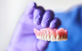 Gloved hand holding an upper denture