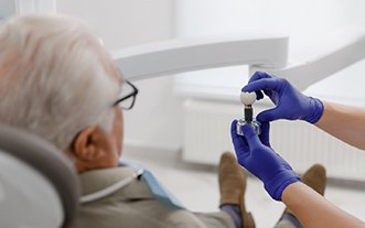 Dentist showing patient a dental implant in Glastonbury, CT