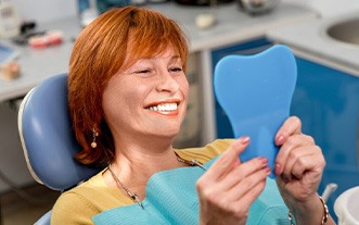 Woman admiring her smile in small mirror
