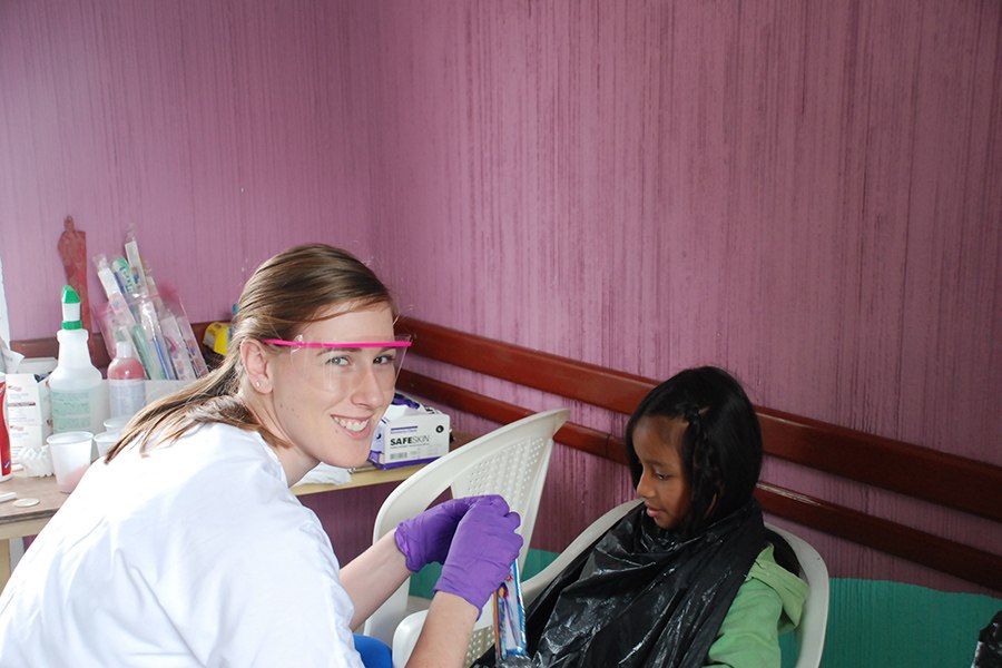 Dental team member smiling as she gives young patient a toothbrush