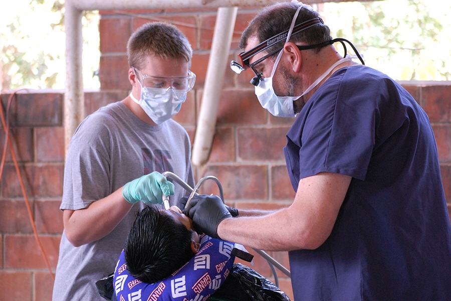 Dentist and team member treating young dental patient