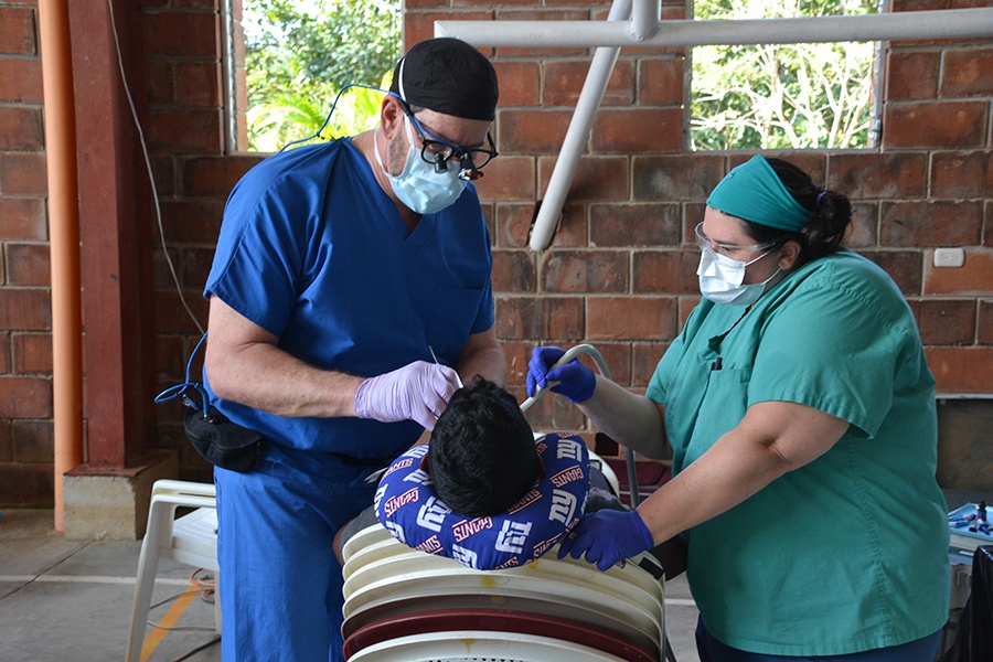 Dentist and team member treat young dental patient on mission trip