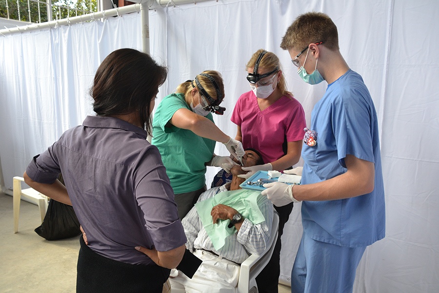 Team members performing and observing dental treatment