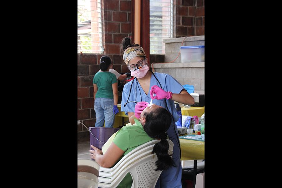 Dental team member cleaning dental patient's teeth