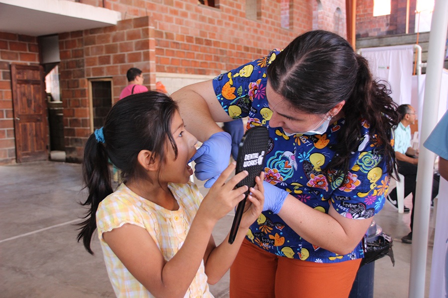 Dental team member showing young patient her smile in mirror