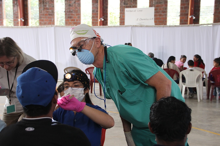 Dental team member and dentist examining patient's smile