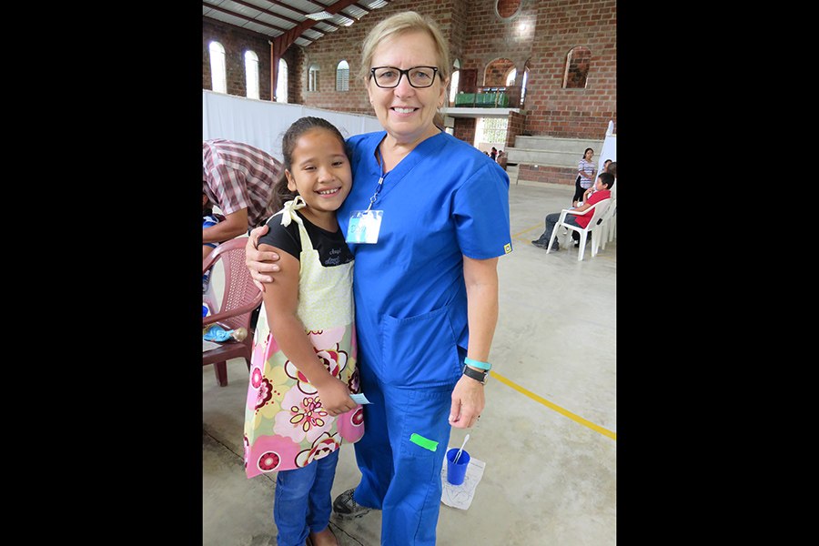 Dental team member giving young patient a hug