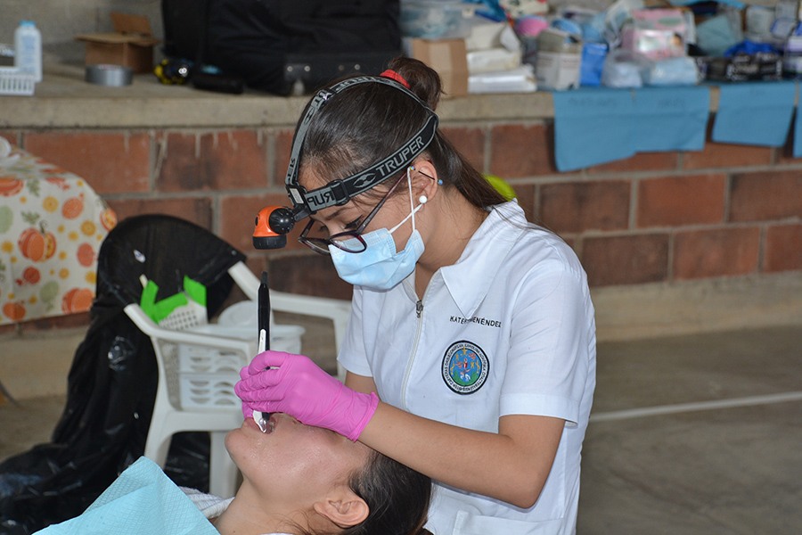 Dental team member using head lamp to examine patient's teeth