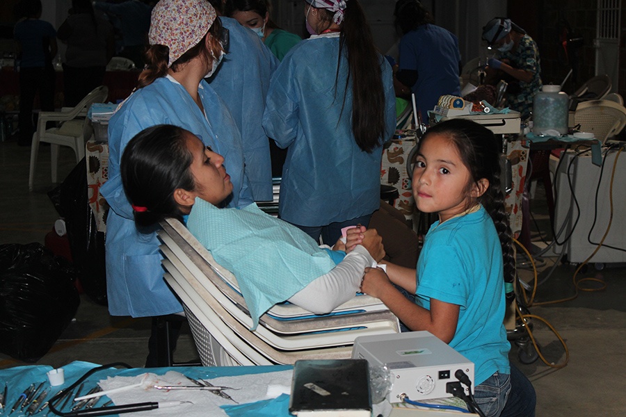 Woman receiving dental care as her young daughter holders he hand