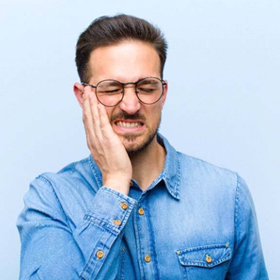 Man with a toothache in Glastonbury touching his face