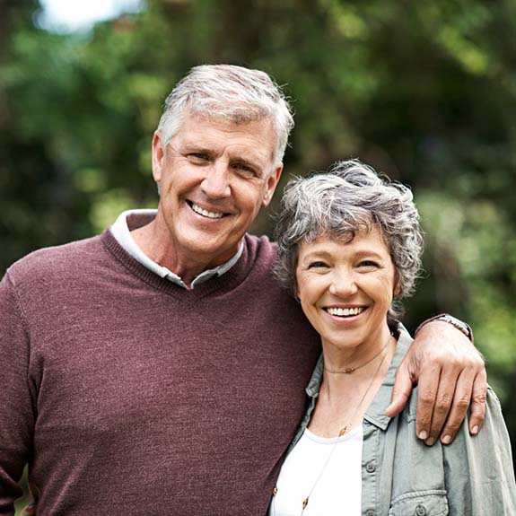 Smiling couple outside with dental implants in Glastonbury