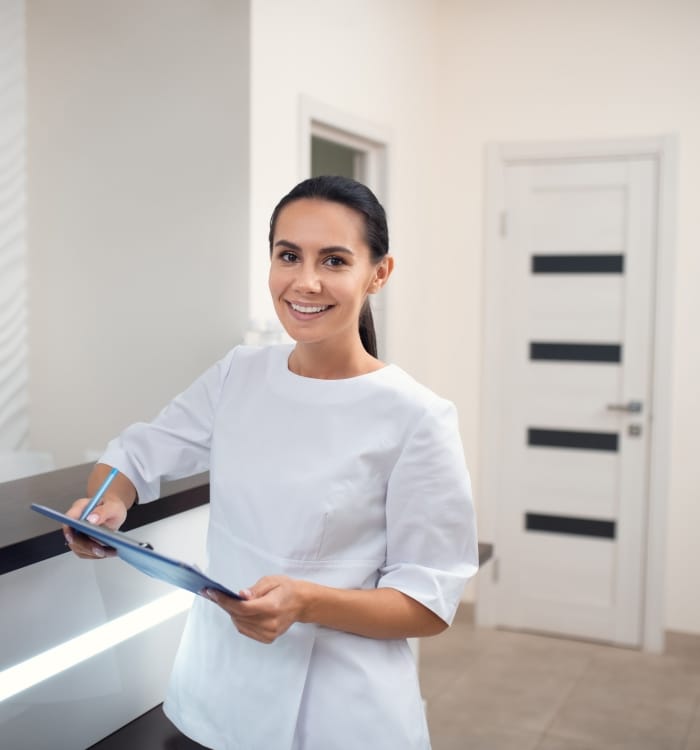 Smiling detnal team member holding dental insurance forms