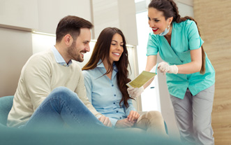 Smiling couple reviewing pamphlet with dental assistant