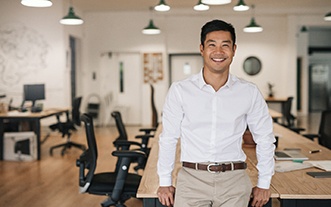 Man in white shirt leaning on table and smiling