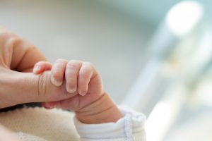 A newborn’s hand clasping its parent’s finger.