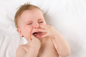 A teething baby lying in a crib. 