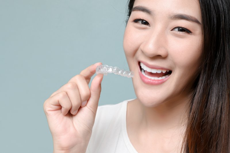 Woman on grey background holding Invisalign in Glastonbury