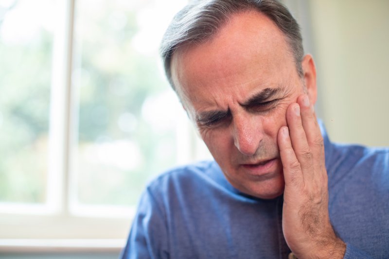 Man holding cheek and ready to call dentist in Glastonbury